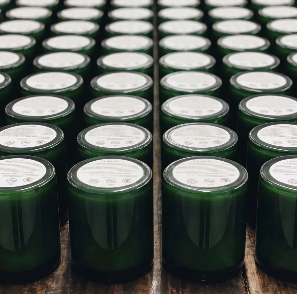Deep green glass candles arranged on a wooden studio table